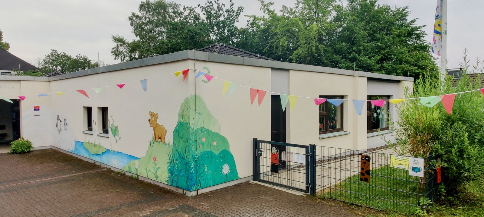 Eingang des Ev. Kindergartens Volmarstein mit bunter Wandbemalung und Wimpelkette
